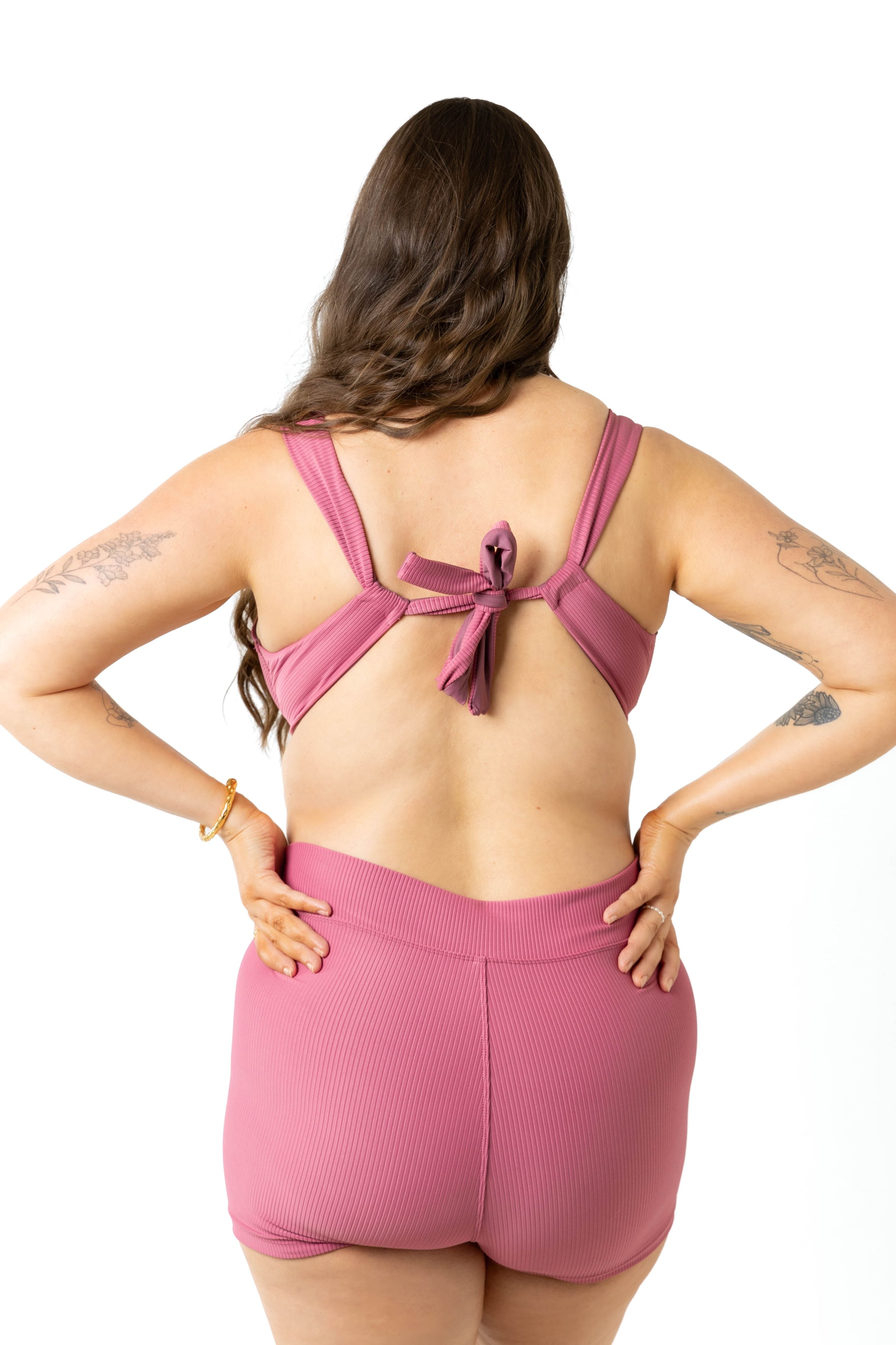 This image features a woman at a photography studio facing back to camera wearing the Harlow Underwire Bikini Top in a vibrant spice color, paired with the campbell swim shorts. The bikini top is specifically designed for DD+ cup sizes, providing ample support with its underwire construction.