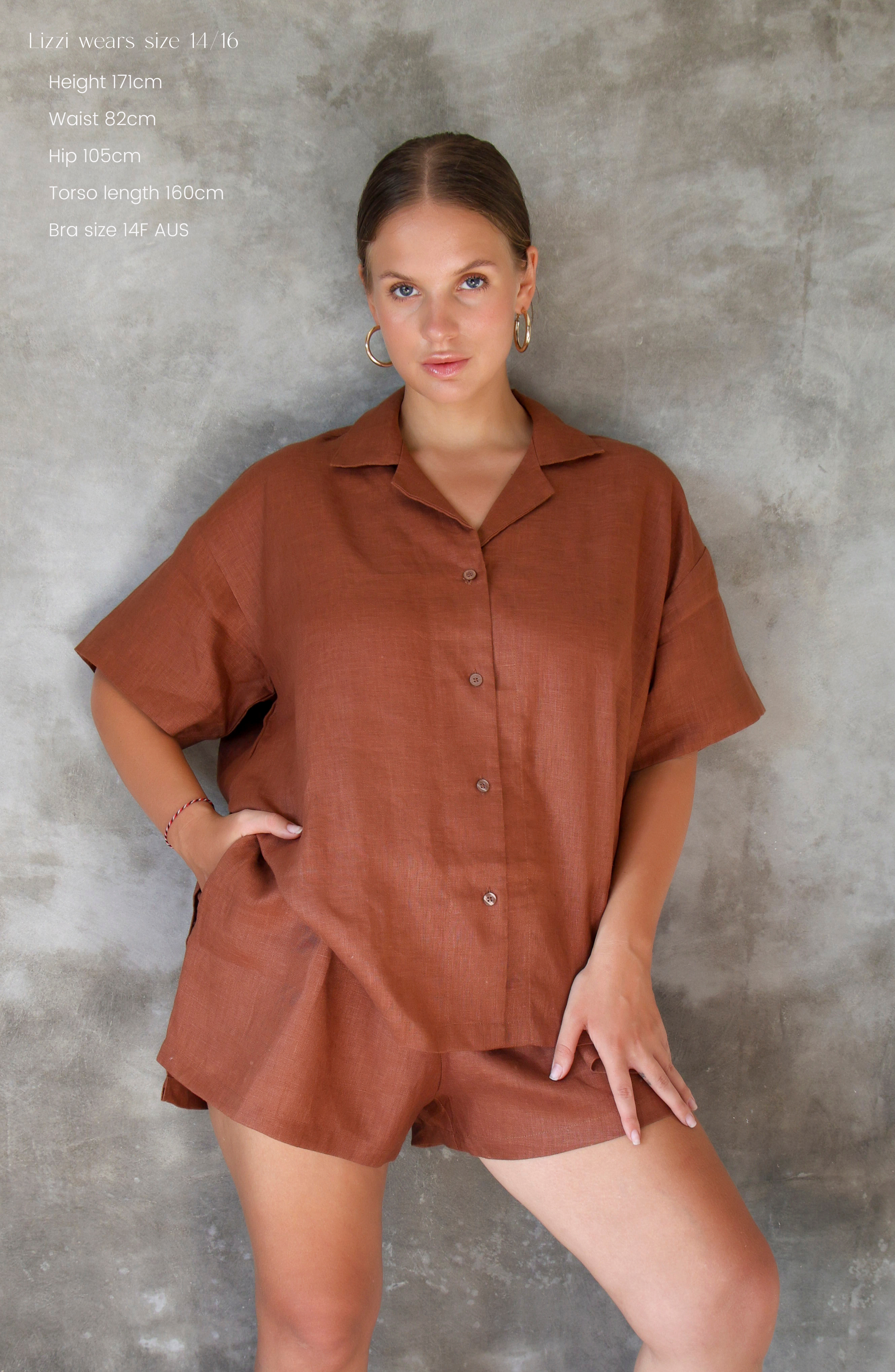 Woman wearing a brown linen shirt and shorts set outfit against a grey background