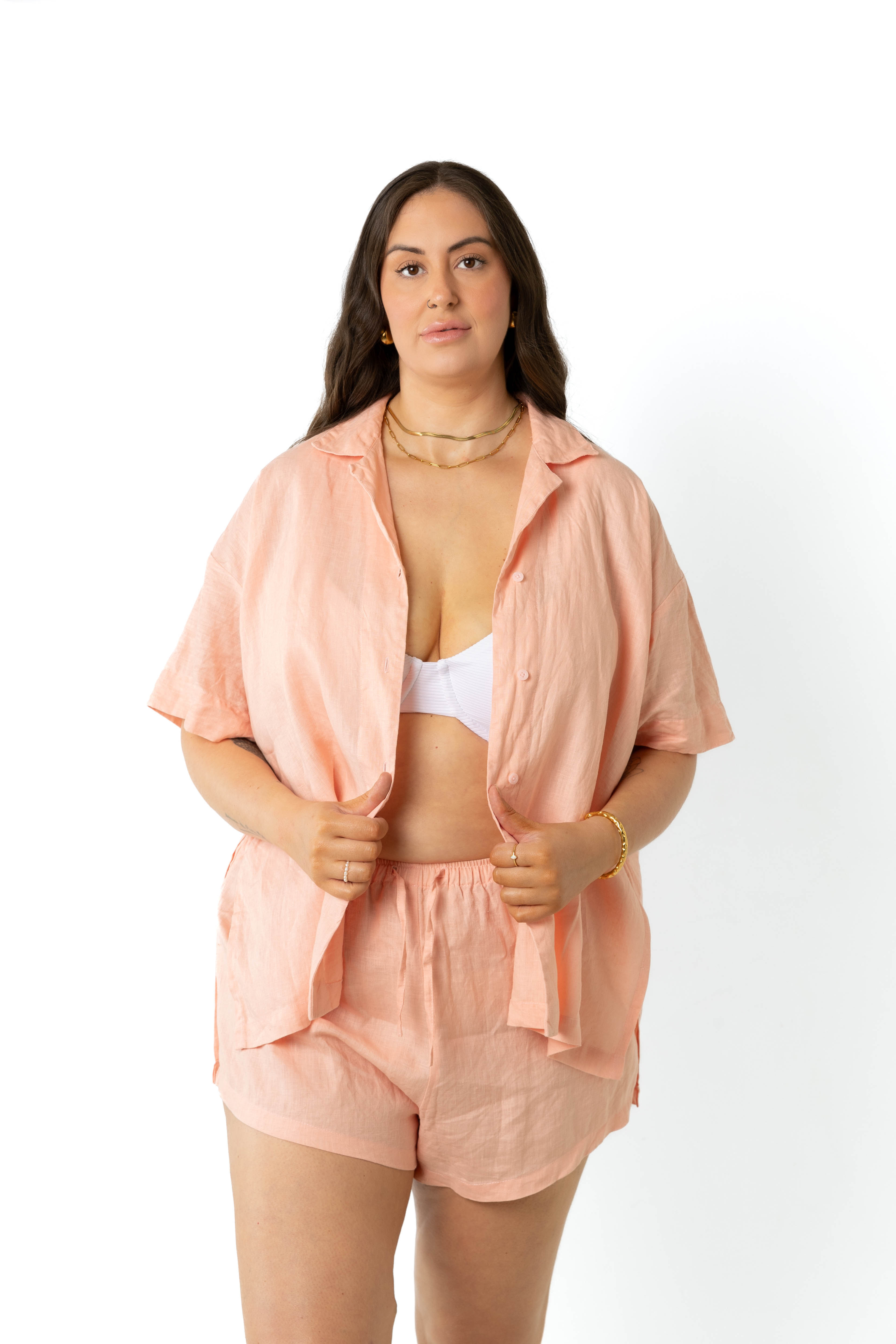 model wears size 18/20 Klum peach organic linen shirt and shorts set size inclusive, untucked, undone short and model holds shirt.