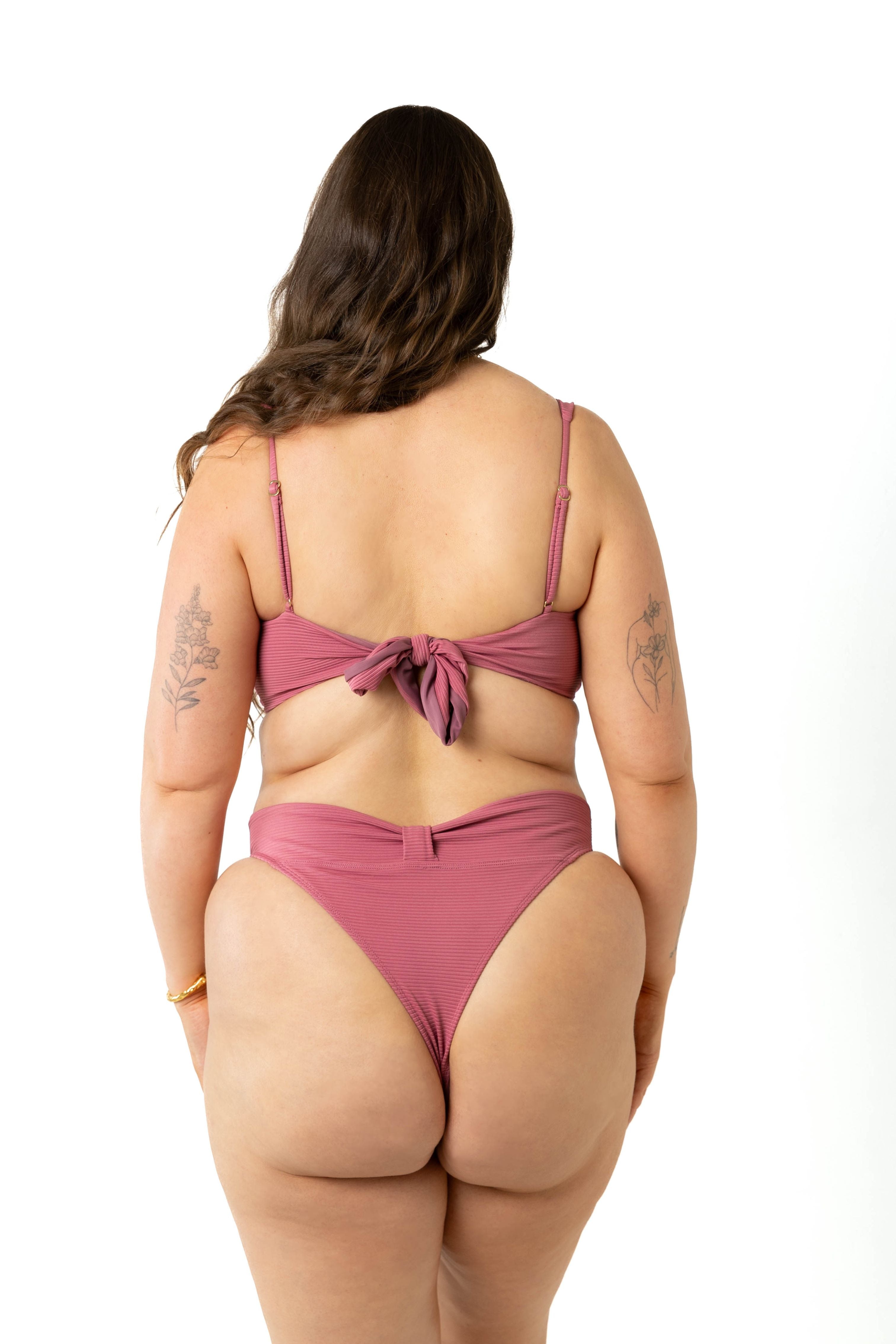 size 18 model wearing the yasmeen bikini crop top and high-cut leg bikini bottoms in colour spice pink, back view.