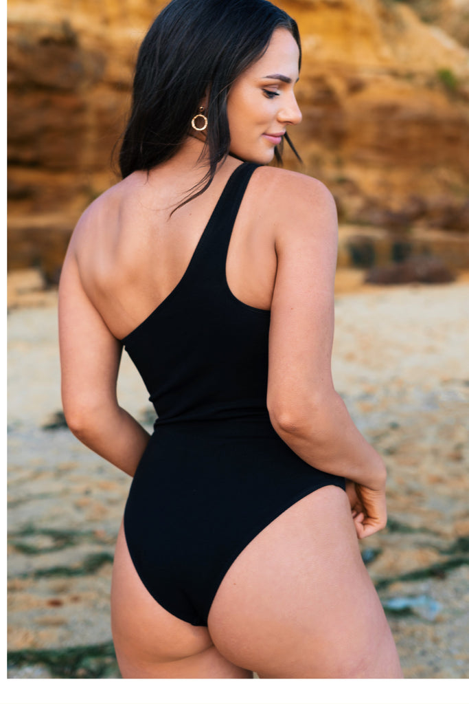Athena one shoulder one piece in black made with ribbed material and fuller coverage bottom.