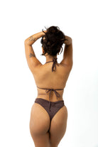 Woman in studio on white background wearing a chocolate brown triangle bikini top and chocolate brown high cut leg bikini bottoms. Back view